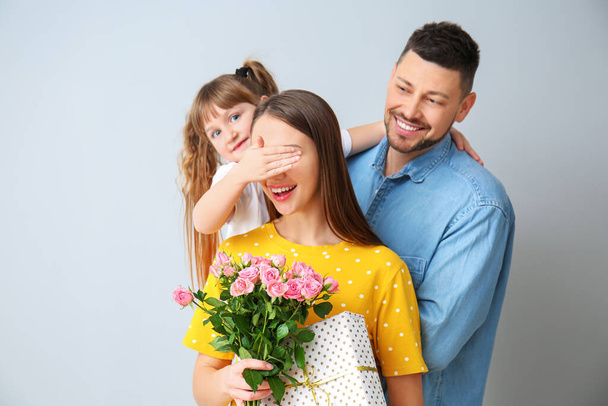 Mann und kleine Tochter begrüßen Frau zum Muttertag auf grauem Hintergrund - Foto, Bild