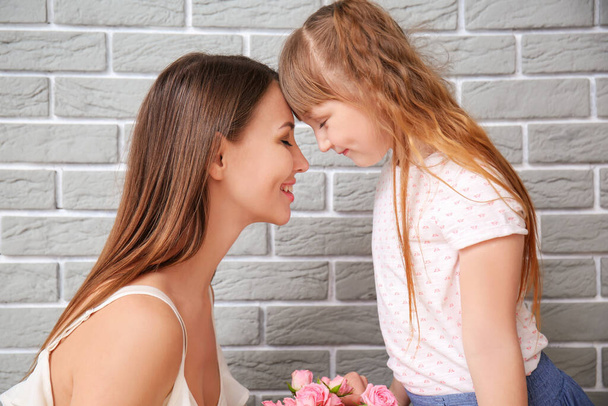 Little daughter greeting her mother near grey brick wall - Photo, image