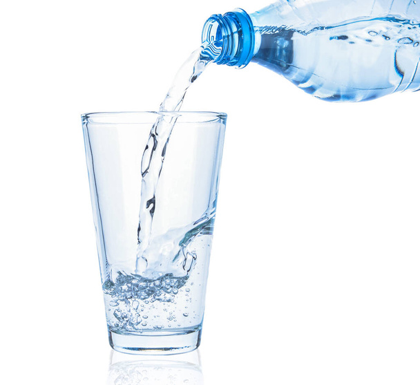 Gieten van zoet water in glas op witte ondergrond - Foto, afbeelding