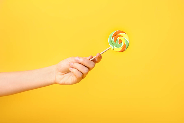 Female hand with sweet lollipop on color background - Foto, Bild