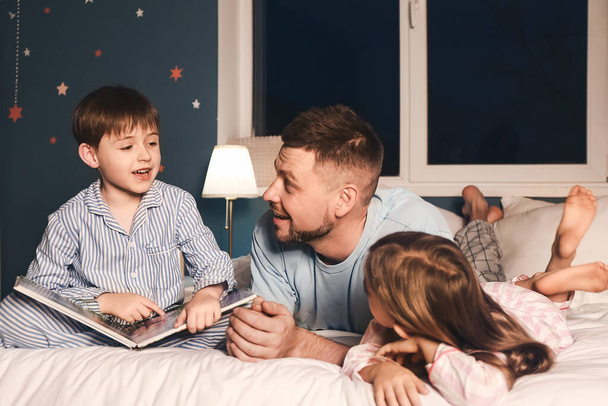 Батько і його маленькі діти читають історію сну вдома
 - Фото, зображення