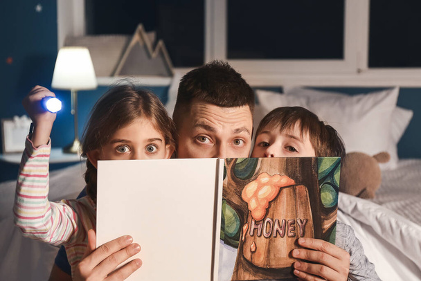 Ο πατέρας και τα παιδιά του διαβάζουν παραμύθια στο σπίτι. - Φωτογραφία, εικόνα