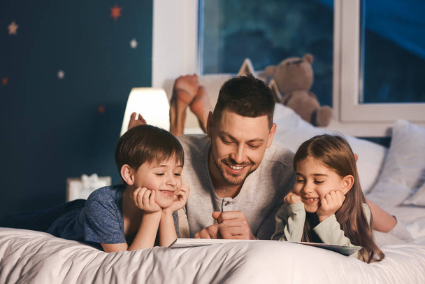 Papà e i suoi bambini che leggono la favola della buonanotte a casa
 - Foto, immagini