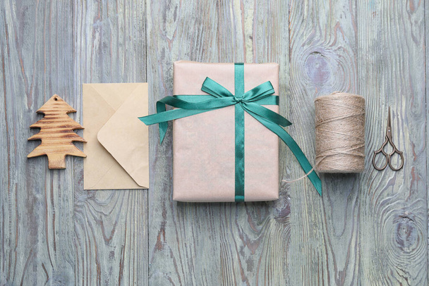 Belo presente para o Natal com envelope e suprimentos em fundo de madeira
 - Foto, Imagem
