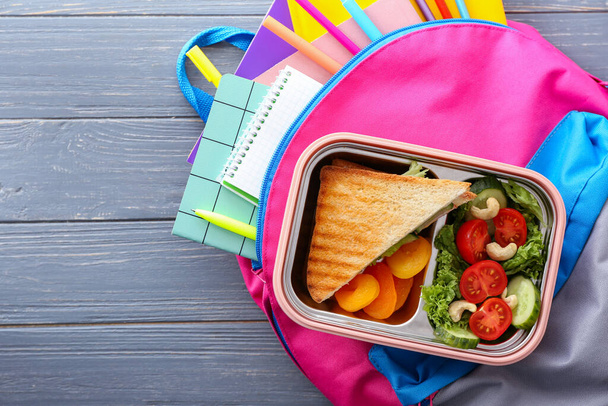 Lunch box and schoolbag on wooden background - Photo, Image