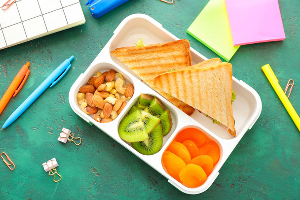 School lunch box with tasty food and stationery on table - Photo, image