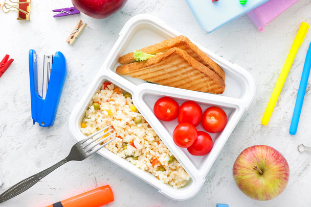 School lunch box with tasty food and stationery on table - Photo, Image