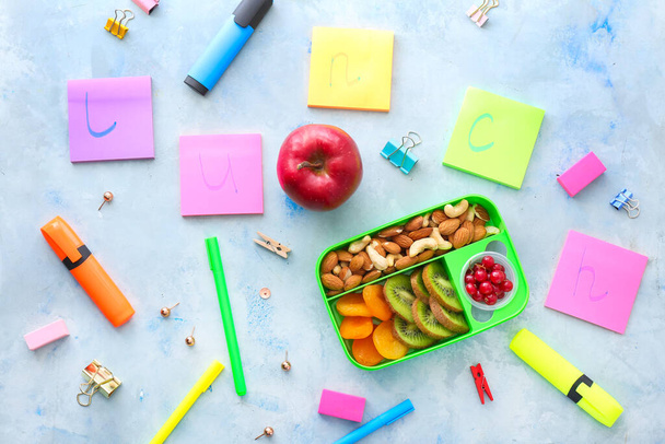 School lunch box with tasty food and stationery on table - 写真・画像