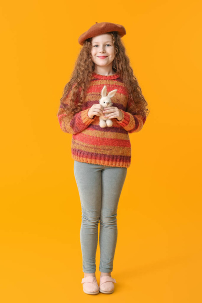 Мила дівчинка з іграшковим кроликом на кольоровому фоні
 - Фото, зображення
