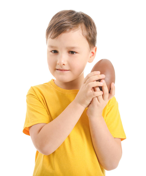 Cute little boy with sweet chocolate egg on white background - Photo, Image