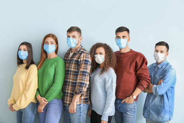 Group of people with protective masks on light background. Concept of epidemic - Photo, Image
