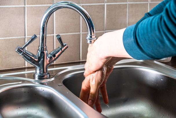 Proper washing of hands demonstrated at steel kitchen sink - Valokuva, kuva