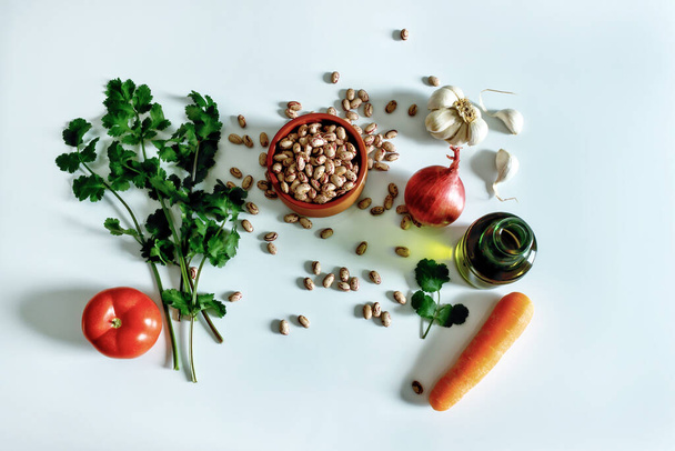 Set of products for making a recipe from legumes: phaseolus,  tomatoes, onions, olive oil, carrots, garlic and herbs. - 写真・画像
