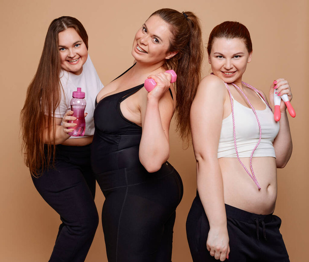 Iloinen ylipainoisille naisille poseeraa kuntosalilla
 - Valokuva, kuva