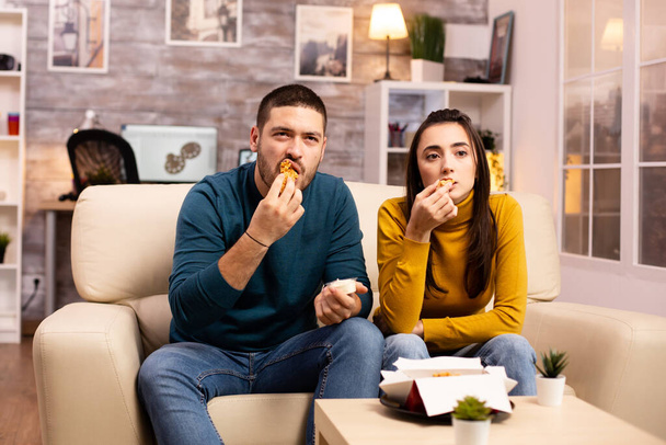 Jeune couple mangeant du poulet frit devant la télé
 - Photo, image