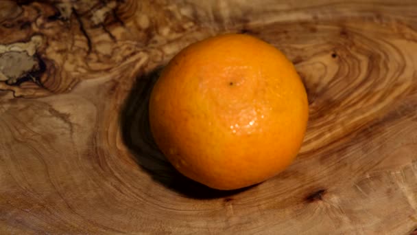 a man cuts a tangerine on a wooden Board with a sharp knife - Imágenes, Vídeo