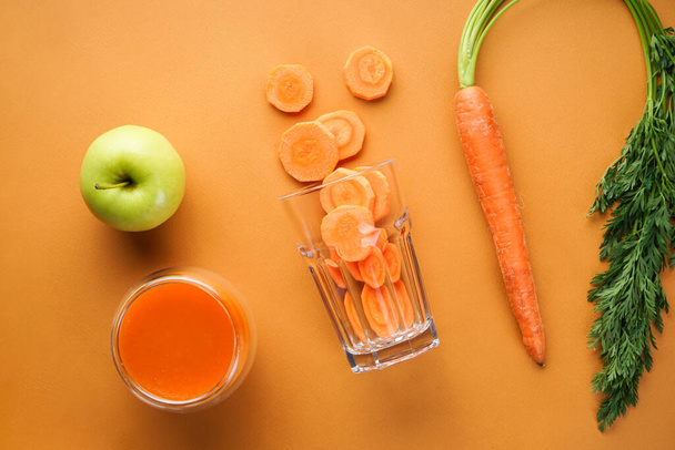 Плоский лежал. Свежий морковный сок, яблоко и свежая морковь на коричневом фоне. Крупный план
. - Фото, изображение