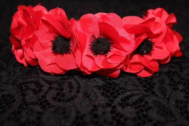 Bezel of red poppies on a black background. Red poppies from the fabric. Hairpin red. Hairpin with poppies. - Photo, Image