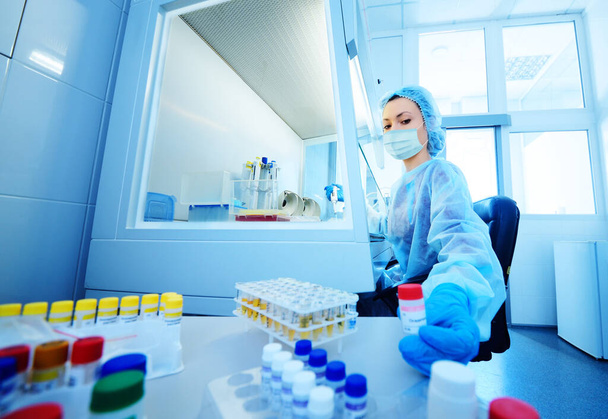 científica femenina en una máscara médica protectora y guantes de goma hace pruebas de ADN PCR en un laboratorio químico y bacteriológico moderno
. - Foto, imagen