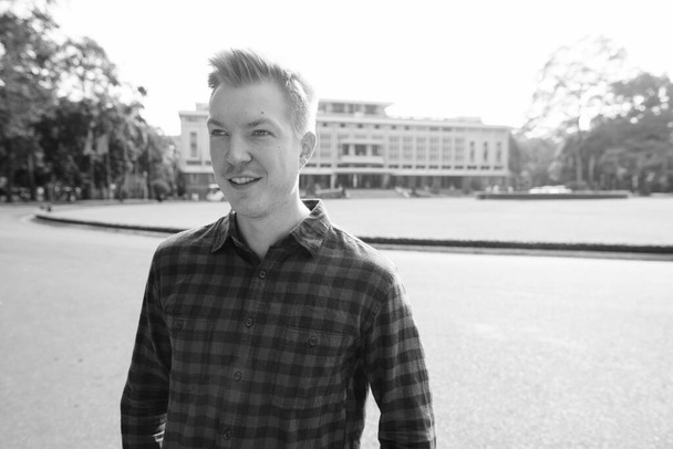 Portrait of young handsome tourist man exploring Ho Chi Minh city in Vietnam in black and white - Foto, imagen