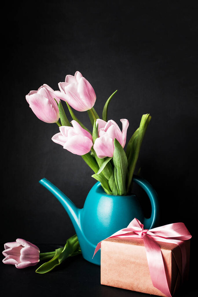 A beautiful bouquet of pink tulips in a water can on a dark background. A place for text. - Photo, Image