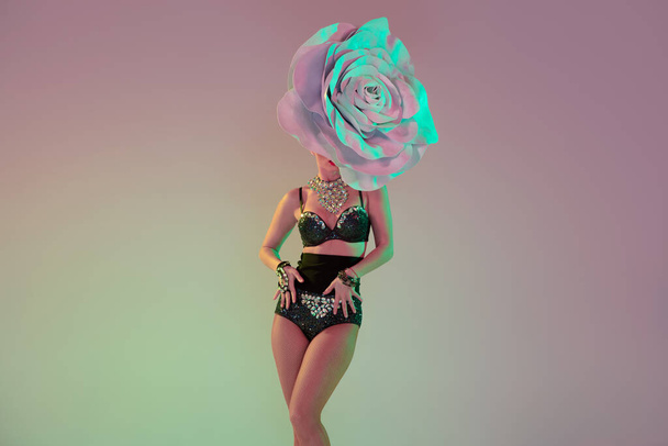 Young female dancer with huge floral hats in neon light on gradient background - Zdjęcie, obraz