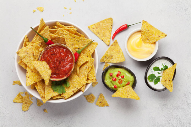 Mexikói nachos chips különböző szószokkal - guacamole, salsa, sajt és tejföl. Top view lakás feküdt kőasztalra - Fotó, kép