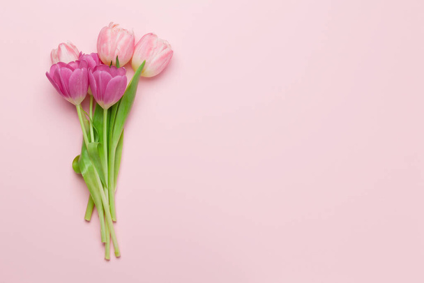 ピンクの背景にチューリップの花とイースターグリーティングカード。トップビューフラットレイアウトあなたの挨拶のためのスペース - 写真・画像