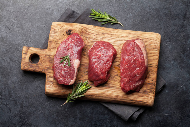 Fillet mignon friss nyers marhahús fűszerekkel a vágódeszkán. Top view lapos fektetés - Fotó, kép