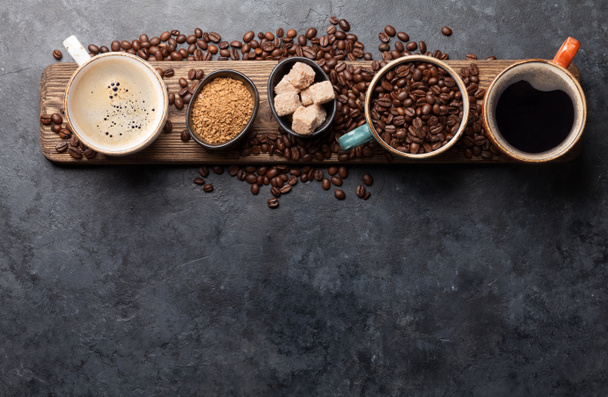 Xícaras de café, açúcar e grãos torrados na mesa de pedra escura. Vista superior com espaço de cópia. Depósito plano
 - Foto, Imagem