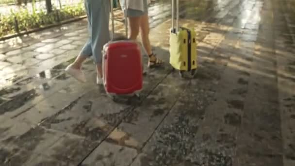 Zwei attraktive junge Touristinnen fotografieren Sehenswürdigkeiten, während sie mit Koffern auf einem Stadtboulevard spazieren gehen - Filmmaterial, Video