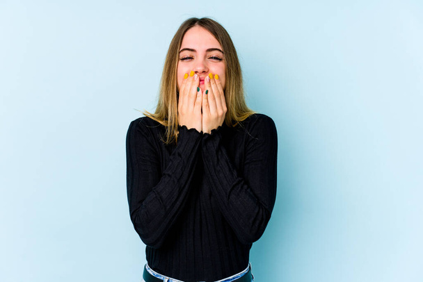Young caucasian woman isolated on blue background laughing about something, covering mouth with hands. - Foto, Imagem