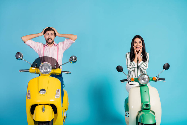 Positive crazy energetic two bikers man woman drive power motor bikes look incredible discount ads impressed touch hands cheeks face scream isolated over blue color background - 写真・画像