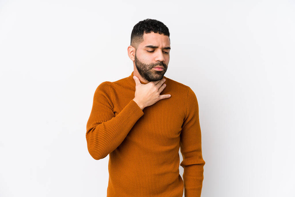 Hombre latino joven contra un fondo blanco aislado sufre dolor de garganta debido a un virus o infección
. - Foto, imagen