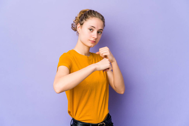 Young caucasian woman on purple background throwing a punch, anger, fighting due to an argument, boxing. - Foto, Imagem