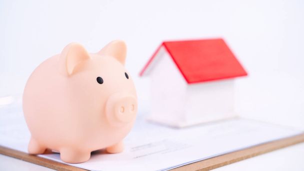 Finansowy koncpet - Piggy bank, piękny czerwony biały drewniany dom model na białym tle, oszczędzając pieniądze na ubezpieczenie, zbliżenie, przestrzeń na ksero. - Zdjęcie, obraz