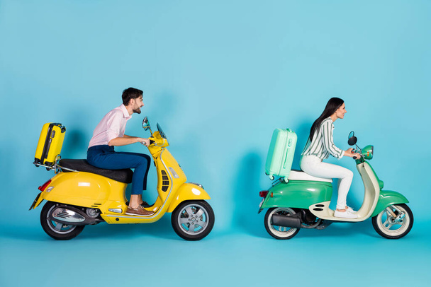 Full length profile photo of rushing airport lady guy drive two retro moped big speed bring rolling suitcases travelers formalwear clothes isolated blue color background - 写真・画像