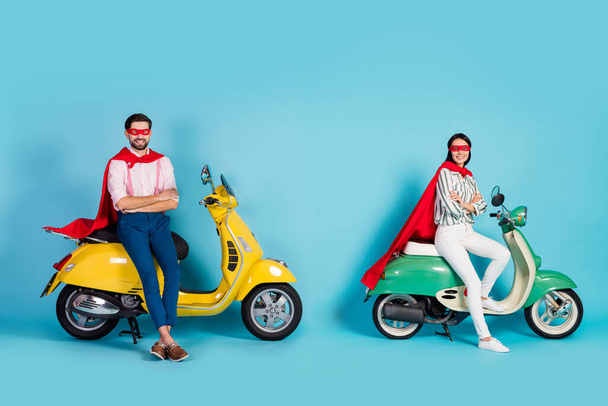 Full size profile photo of funny lady guy arms crossed sitting two vintage moped wear red cape mask ready for halloween party play super heroes role isolated blue color background - Φωτογραφία, εικόνα