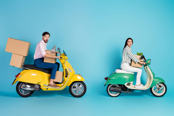 Full length photo astonished man woman bikers drivers get property mortgage drive motor bike carry papercard packages lamp flower wear formalwear outfit isolated blue color background - Foto, imagen