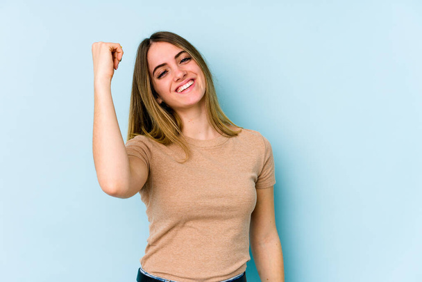 Young caucasian woman isolated on blue background celebrating a victory, passion and enthusiasm, happy expression. - Photo, image
