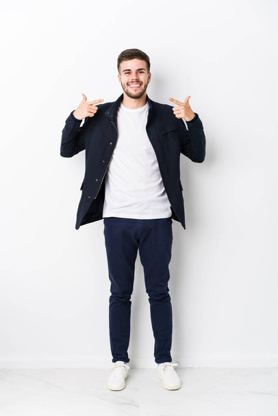 Full body young caucasian man isolated smiles, pointing fingers at mouth. - Foto, Bild