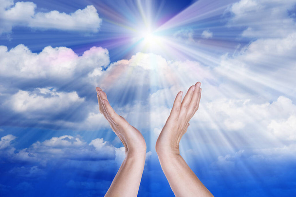 Mãos de cura no céu com sunburst brilhante
 - Foto, Imagem