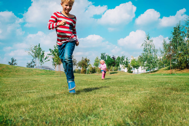 ευτυχισμένο αγόρι και κορίτσι τρέχουν και παίζουν στη φύση του καλοκαιριού - Φωτογραφία, εικόνα