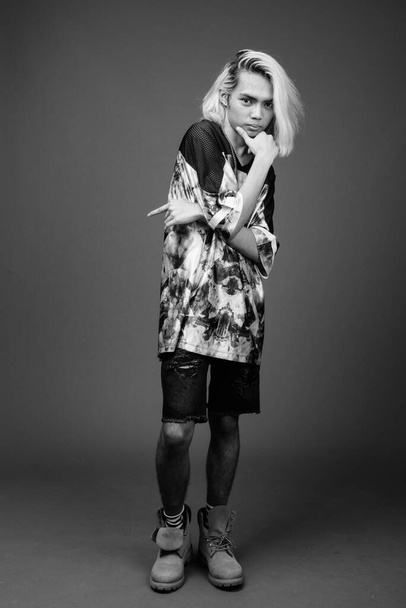 黒と白で灰色の背景にスタイリッシュな服を着て若いフィリピン人男性のスタジオショット - 写真・画像
