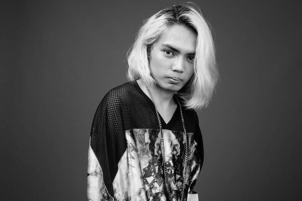 Studio shot of young Filipino man wearing stylish clothes against gray background in black and white - Photo, Image