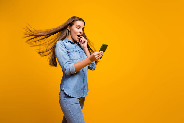Profile photo of beautiful lady hold telephone walk down street hairstyle flying addicted user blogger wear casual jeans denim outfit isolated yellow color background - Zdjęcie, obraz