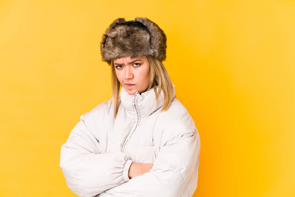 Młoda blondynka kaukaska kobieta nosi zimowe ubrania odizolowane zmarszczki twarzy w niezadowoleniu, trzyma ręce złożone. - Zdjęcie, obraz
