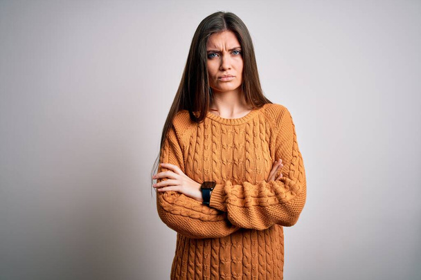 Young beautiful woman with blue eyes wearing casual sweater standing over white background skeptic and nervous, disapproving expression on face with crossed arms. Negative person. - Fotó, kép