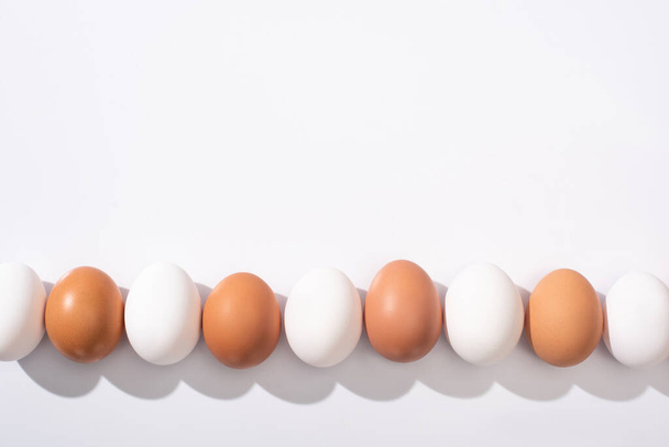 top view of white and brown chicken eggs on white surface - Foto, afbeelding