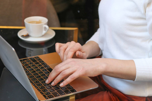 Mulher de negócios sentada em restaurante com laptop e café e digitação
 - Foto, Imagem